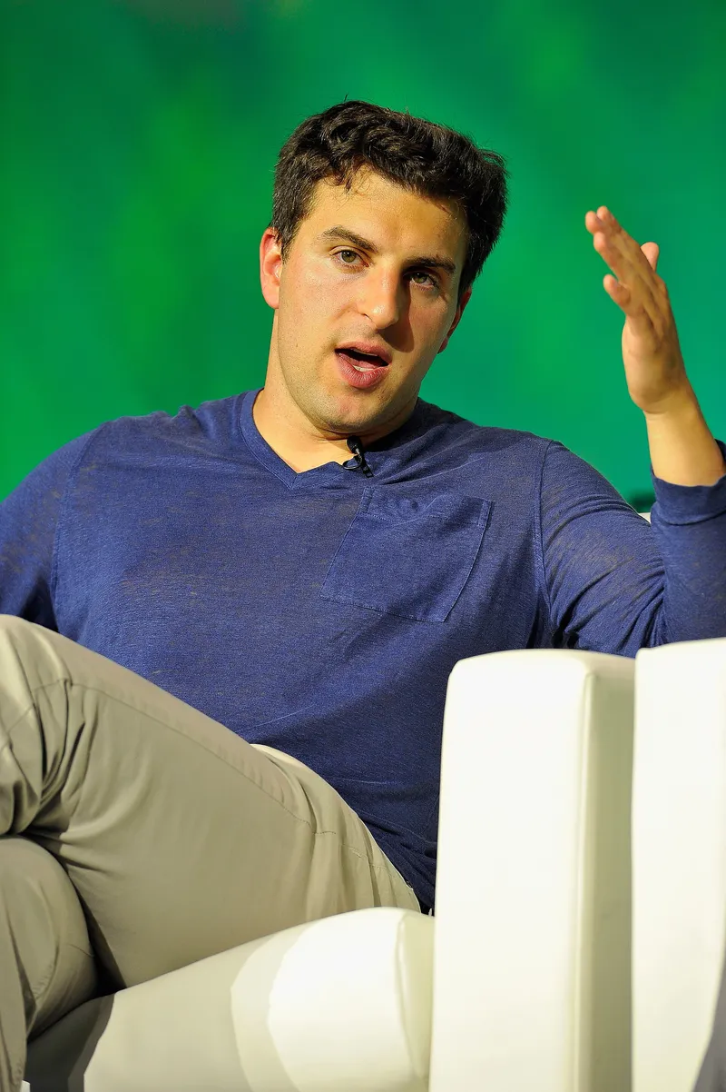 Brian Chesky speaking onstage at TechCrunch Disrupt in San Francisco, gesturing as he talks.